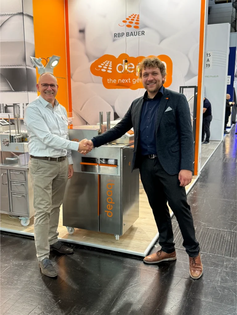 Herr Henri Engel von der RBP-Bauer GmbH, Handschlag mit Timo Heinen von Heinen Industriedesign vor der neuen Blister Maschine, präsentiert auf der Interpack 2026 in Düsseldorf
